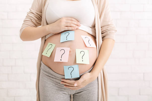 a pregnant woman with question marks on her stomach, meant to symbolize pregnancy myths and misconceptions.
