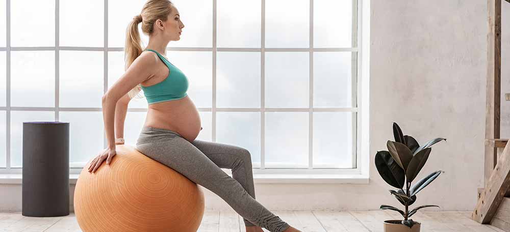 A pregnant woman working out on an inflatable ball.
